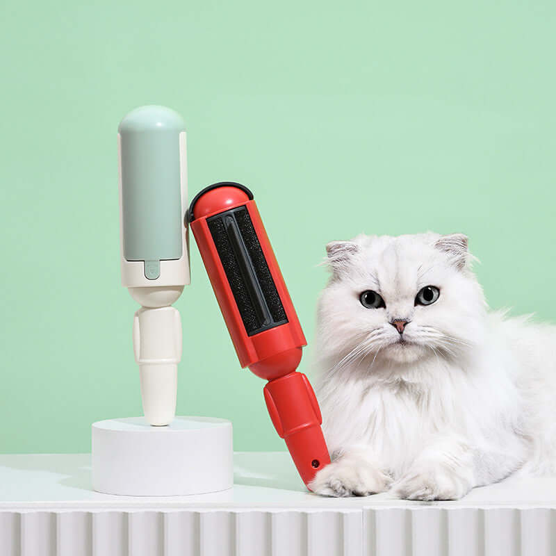 Portable pet hair roller in red and green colors displayed beside a fluffy white cat on a light background.