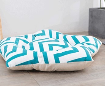 Stylish teal and white chevron patterned floor cushion for comfortable seating.